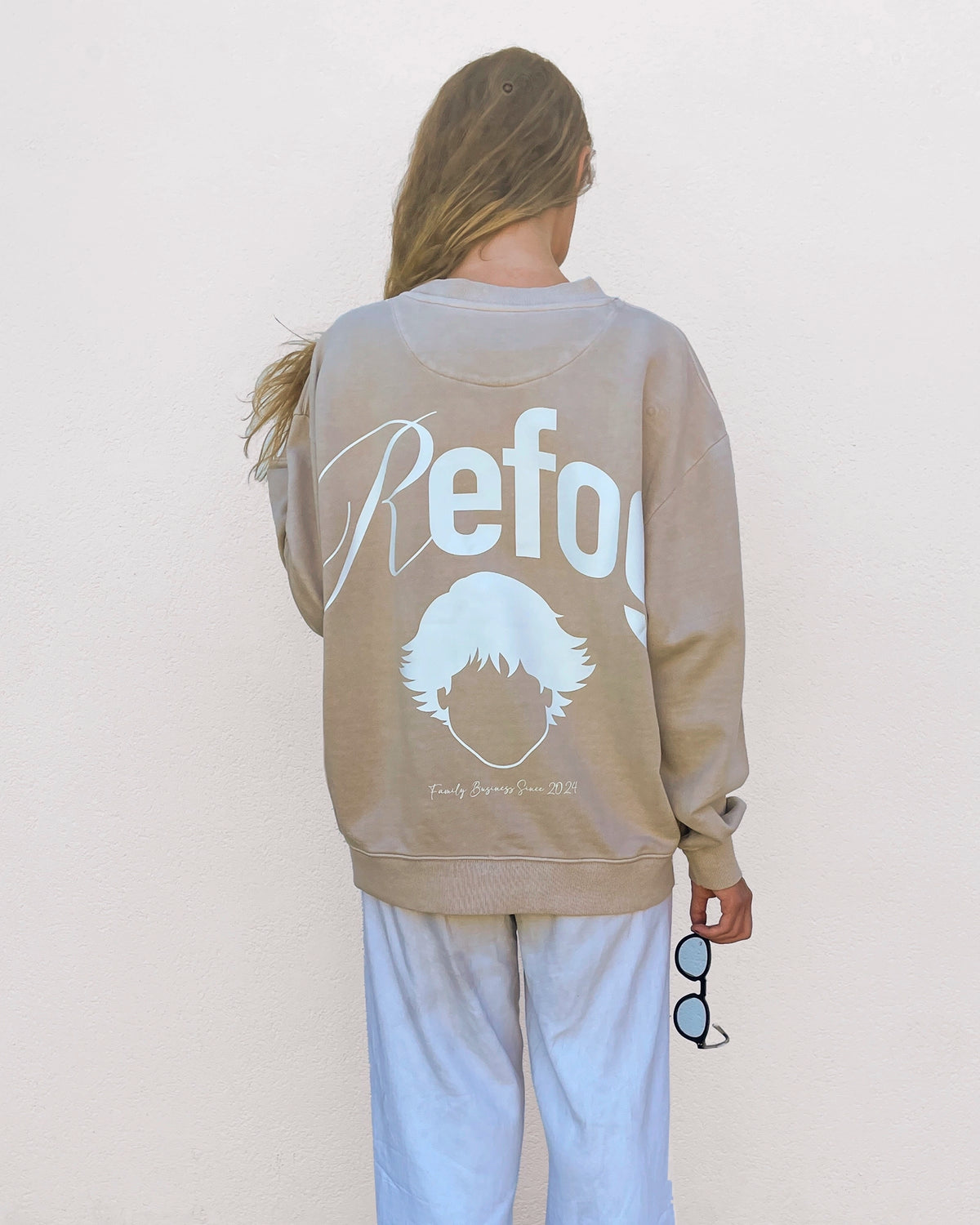 Mujer con Signature Crewneck Beige de Refog mostrando el gráfico trasero de gran formato.