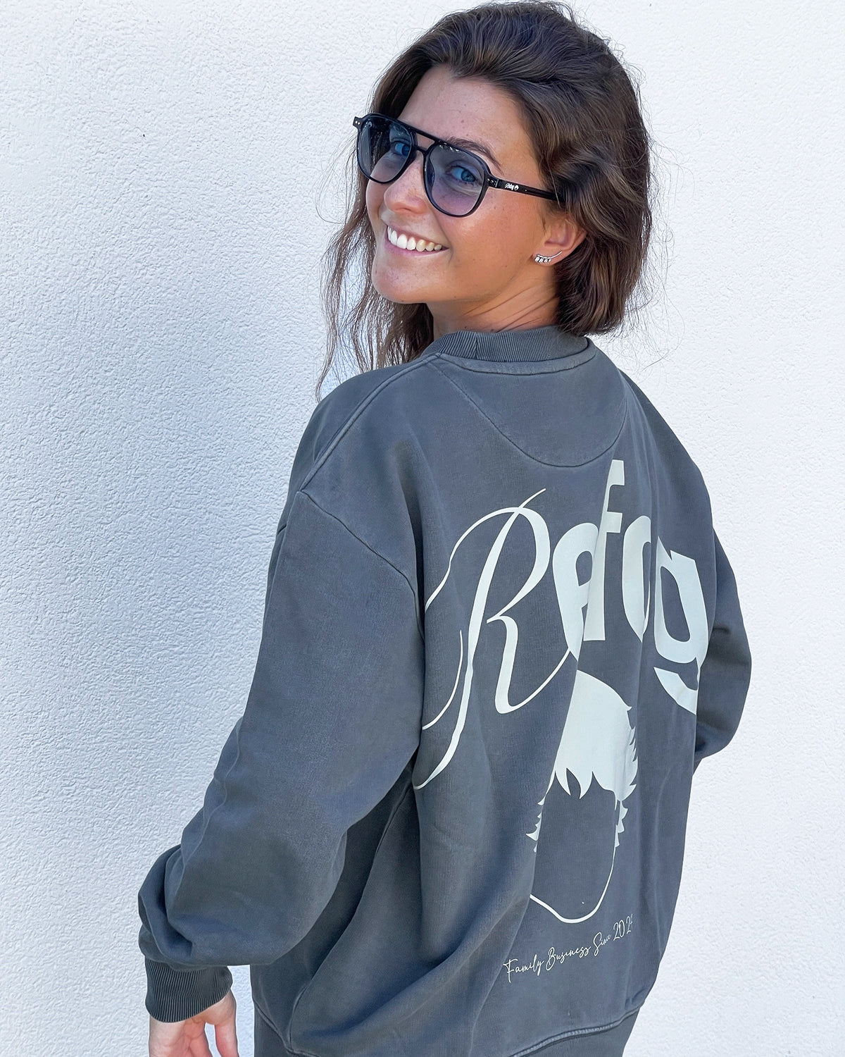 Mujer con Signature Crewneck Grey de Refog mostrando el gráfico trasero de gran formato.