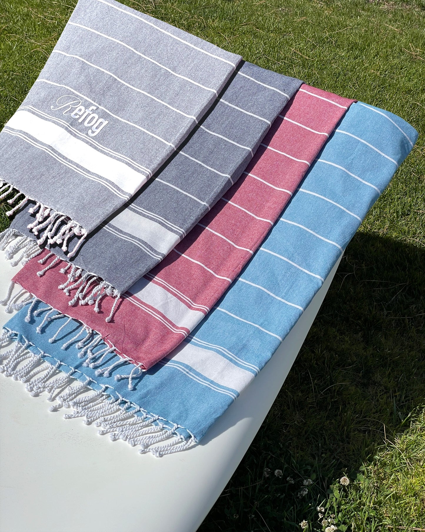 Toallas Refog en varios colores sobre exterior con diseño de rayas y flecos