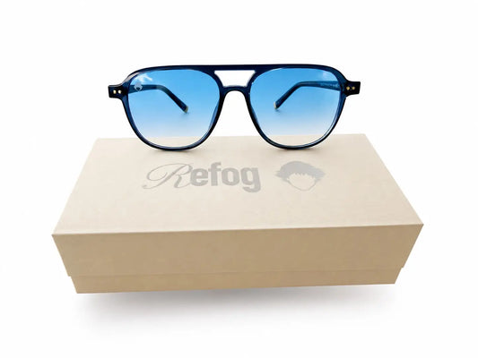 Gafas de sol Ocean de Refog con montura azul translúcida y lentes azul degradado sobre caja personalizada.