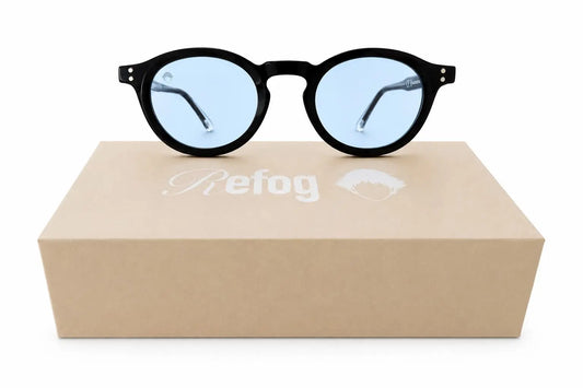 Gafas de sol Round Tardeo de Refog con montura negra redonda y lentes azul claro sobre caja personalizada.