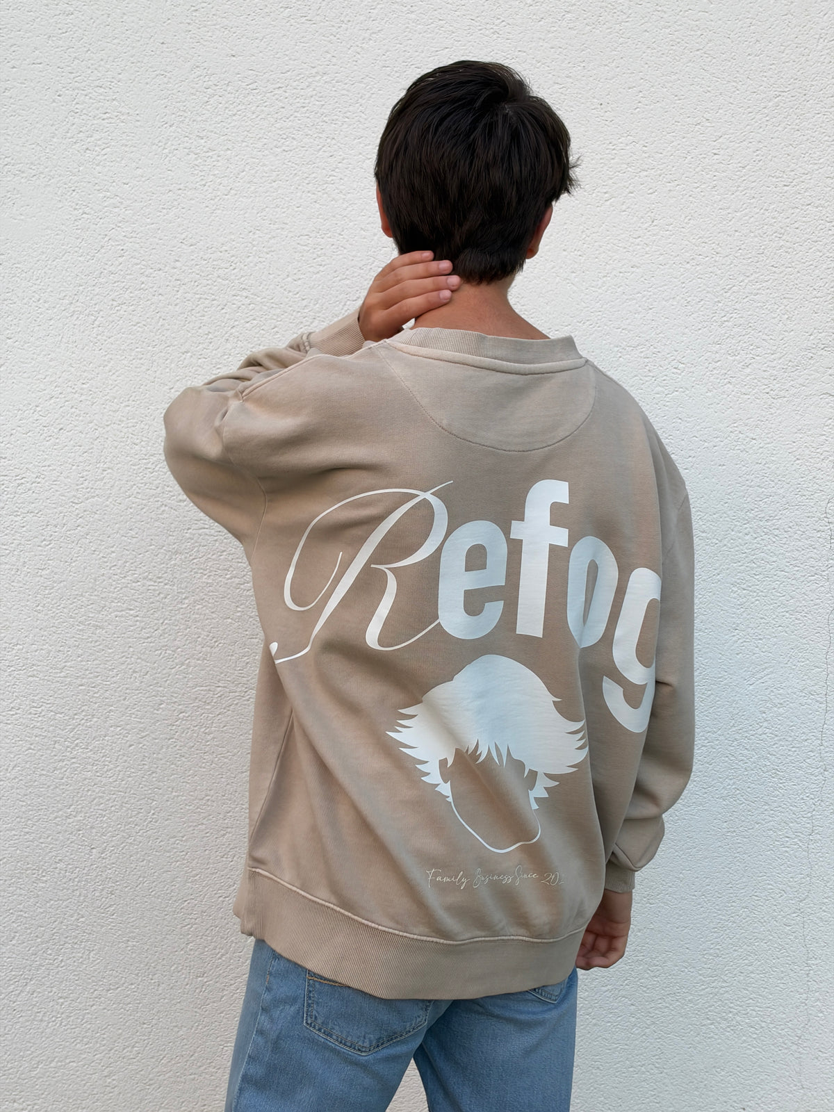 Hombre con Signature Crewneck Beige de Refog mostrando el gráfico trasero de gran formato.