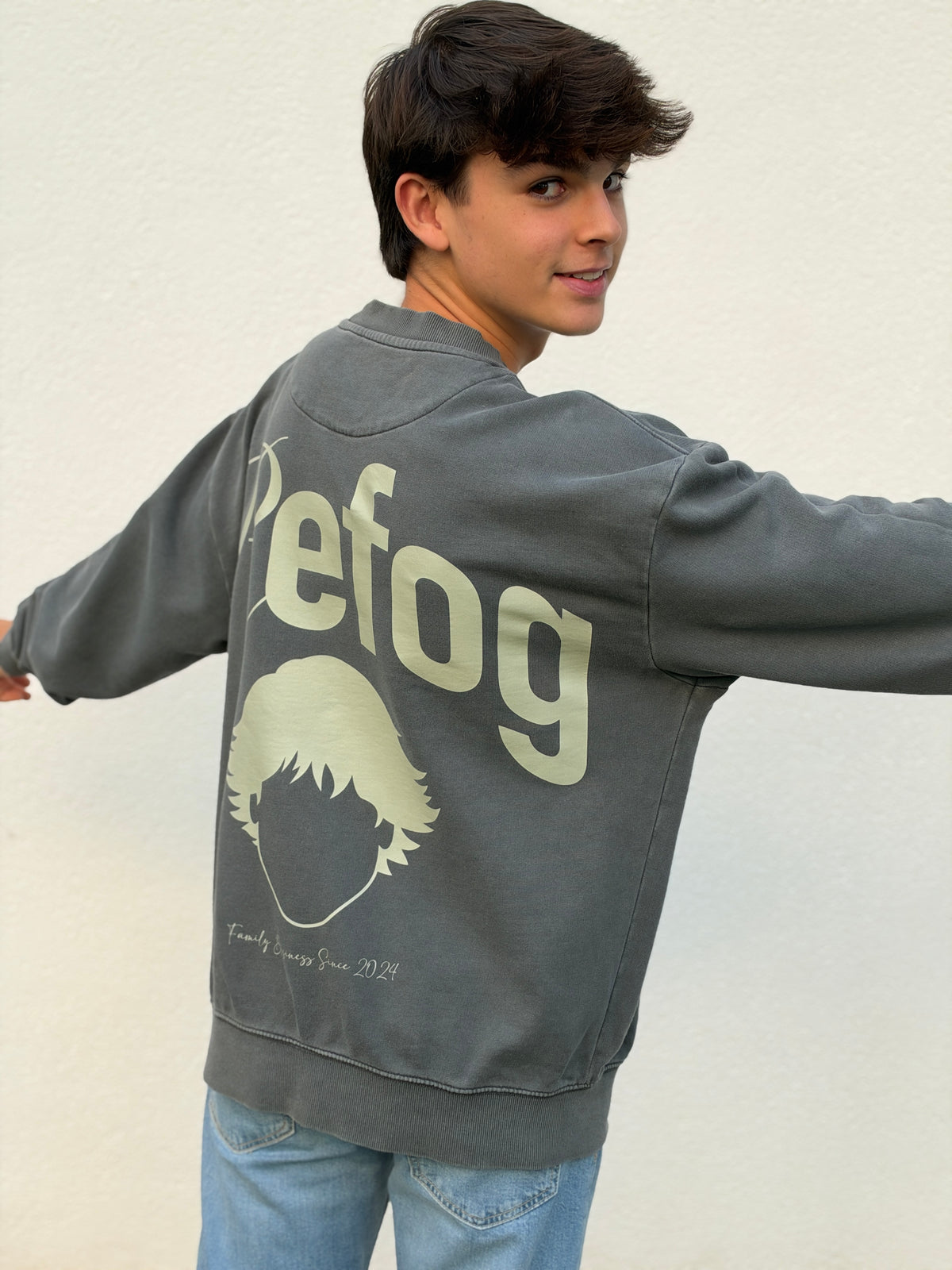 Hombre con Signature Crewneck Grey de Refog mostrando el gráfico trasero de gran formato.